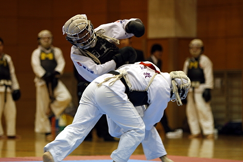 平成21年度日本拳法連盟鏡開き式 赤：小畑 二段（立教大学） vs 白：三吉 初段（國士舘）、小畑の両脚タックル（双手刈）をかわす三吉。
_MG_1974.JPG