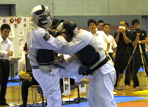 日本拳法全国選抜社会人選手権大会 社会人大会：準々決勝・代表者決定戦。赤：陸自大宮A・太田vs第1普通科連隊A・秋葉。太田の胴膝蹴り（一本）。密着状態での秋葉の揚げ打ちで1本先取されたあとの反撃。
_MG_0575.JPG