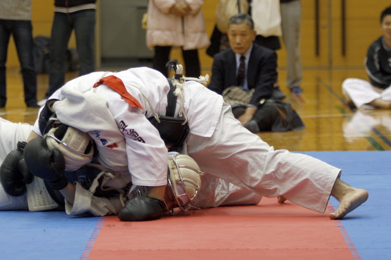 平成27年度日本拳法連盟鏡開き式 段の部、早稲田大学・橋本vs國士舘高校・長谷川。長谷川の押さえヒザ面蹴り（一本）。
_MG_2476.JPG